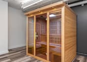 Thumbnail 30 of 46 - A wooden pod with glass doors is in a room with grey walls.