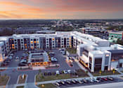 Thumbnail 24 of 37 - A parking lot is in front of a building with a sunset in the background.