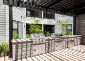 Thumbnail 32 of 71 - the outdoor kitchen has stainless steel appliances and a bar with grill at The Flats & Terraces at Wildhorse Village, Chesterfield, MO