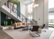Thumbnail 38 of 71 - a living room with a couch and a chair in front of a staircase at The Flats & Terraces at Wildhorse Village, Chesterfield, MO