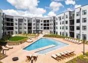 Thumbnail 30 of 71 - an apartment building with a pool and lounge chairs at The Flats & Terraces at Wildhorse Village, Missouri