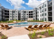 Thumbnail 31 of 71 - an apartment building with a pool and lounge chairs at The Flats & Terraces at Wildhorse Village, Missouri, 63005