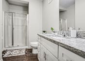 Thumbnail 4 of 23 - A bathroom with a marble countertop and a walk-in shower.