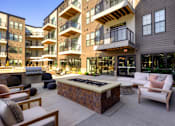 Thumbnail 33 of 36 - A patio area with a fire pit and seating area in front of apartment buildings. at The Cunningham Apartments, West Des Moines