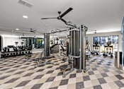 Thumbnail 25 of 36 - A gym with a checkered floor and a variety of equipment. at The Cunningham Apartments, West Des Moines, Iowa