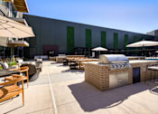 Thumbnail 34 of 36 - A patio area with tables and chairs and a grill. at The Cunningham Apartments, West Des Moines, IA, 50266