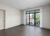 Thumbnail 4 of 28 - Hibernia living room with rich vinyl plank flooring and large sliding glass doors with custom window coverings leading out to a private balcony at Hibernia Apartments, St Louis, MO, 63139