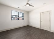 Thumbnail 6 of 28 - Hibernia bedroom with rich vinyl plank flooring, oversized windows with white blinds and ceiling fan at Hibernia Apartments, Missouri