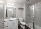 Thumbnail 8 of 28 - Hibernia bathroom with white cabinets, oversized mirror and sliding glass door shower at Hibernia Apartments, St Louis