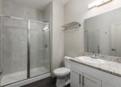 Thumbnail 9 of 28 - Hibernia bathroom with white cabinets, oversized mirror and sliding glass door shower at Hibernia Apartments, St Louis, MO