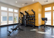 Thumbnail 23 of 28 - A gym with a bench, weights, and a bicycle at Montage at Hawk Ridge Apartments, Lake St. Louis, MO 63367