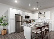 Thumbnail 1 of 28 - A kitchen with a refrigerator, microwave, and a counter with chairs at Hawk Ridge Apartments, Lake St. Louis, Missouri, 63367