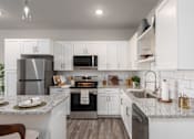 Thumbnail 2 of 28 - A modern kitchen with white cabinets and stainless steel appliances at Hawk Ridge Apartments, Lake St. Louis, 63367