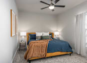 Thumbnail 7 of 28 - A bedroom with a bed, a ceiling fan, and two lamps at Hawk Ridge Apartments, Lake St. Louis, Missouri 63367