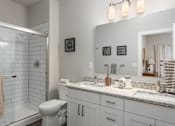 Thumbnail 9 of 28 - A bathroom with a toilet, sink, and mirror at Hawk Ridge Apartments, Lake St. Louis, MO 63367