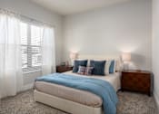 Thumbnail 6 of 28 - A bedroom with a bed, nightstand, and window with curtains at Hawk Ridge Apartments, Lake St. Louis, MO 