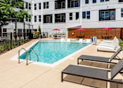 Thumbnail 44 of 47 - a swimming pool with lounge chairs and a building in the background at Grand Flats, St. Louis, 63104