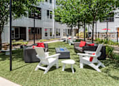 Thumbnail 40 of 47 - an outdoor lounge area with chairs and couches in front of a building at Grand Flats, St. Louis