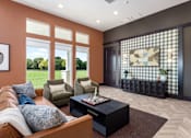 Thumbnail 20 of 28 - A living room with a brown couch, a coffee table, and a window with a view of trees at Montage at Hawk Ridge Apartments, 63367, Missouri