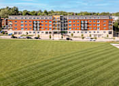 Thumbnail 31 of 33 - A large grassy field in front of a red brick building.