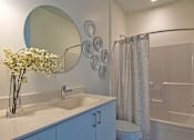 Thumbnail 38 of 39 - Steelcote Lofts bathroom with white cabinetry and white quartz countertops. Large circular mirror and tile at Steelcote Square, St. Louis, 63103