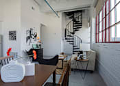 Thumbnail 36 of 39 - Steelcote Lofts dining/living room area with polished concrete floors, white exposed brick walls and black spiral staircase at Steelcote Square, St. Louis, MO