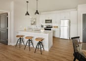 Thumbnail 1 of 19 - a kitchen with white cabinets and a bar with three stools at 44 West Luxury Living, Missouri