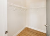 Thumbnail 12 of 19 - a bedroom with white walls and a wood floor and a closet with white hangers at 44 West Luxury Living, Valley Park, MO, 63088