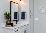 Thumbnail 14 of 36 - A bathroom with a white countertop and a mirror above it at The Cunningham Apartments, West Des Moines