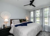 Thumbnail 11 of 36 - A bedroom with a large bed, a ceiling fan, and a window with curtains at The Cunningham Apartments, West Des Moines, Iowa