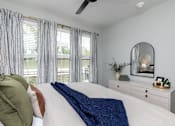 Thumbnail 12 of 36 - A bedroom with a bed, a dresser, and a mirror at The Cunningham Apartments, West Des Moines, IA, 50266