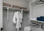 Thumbnail 13 of 36 - A white robe is hanging on a hanger in a closet at The Cunningham Apartments, West Des Moines