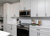 Thumbnail 2 of 36 - A kitchen with white cabinets and a black oven. at The Cunningham Apartments, West Des Moines