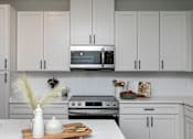 Thumbnail 3 of 36 - A kitchen with white cabinets and a marble countertop. at The Cunningham Apartments, West Des Moines, 50266