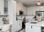 Thumbnail 4 of 36 - A modern kitchen with white cabinets and a white countertop. at The Cunningham Apartments, West Des Moines, 50266