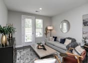 Thumbnail 8 of 36 - A living room with a grey couch, a coffee table, and a round mirror on the wall. at The Cunningham Apartments, Iowa