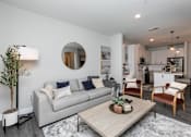 Thumbnail 7 of 36 - A modern living room with a grey couch, a wooden coffee table, and a round mirror on the wall. at The Cunningham Apartments, Iowa