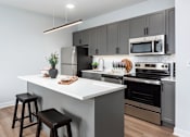 Thumbnail 19 of 39 - model kitchen with stainless steel appliances, plank flooring, kitchen island and at Steelcote Square, St. Louis, MO, 63103