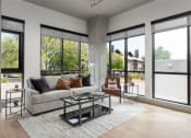 Thumbnail 9 of 58 - a living room with a couch and a table in front of large windows at Bemiston Place Apartments, Missouri, 63105