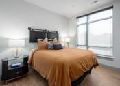 Thumbnail 14 of 58 - a bedroom with a large window and a bed with an orange blanket and pillows at Bemiston Place Apartments, Missouri, 63105