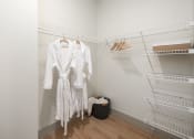 Thumbnail 20 of 58 - two white dresses hanging in a closet with metal shelves at Bemiston Place Apartments, Clayton, 63105