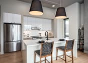 Thumbnail 11 of 58 - a kitchen with a large island and two chairs at Bemiston Place Apartments, Clayton