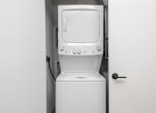 Thumbnail 10 of 71 - a white washer and dryer in a room with a door at The Flats & Terraces at Wildhorse Village, Missouri
