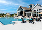 Thumbnail 26 of 34 - A large swimming pool with lounge chairs and a building in the background.