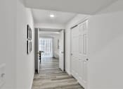 Thumbnail 21 of 33 - A hallway with white doors and a light on the ceiling.
