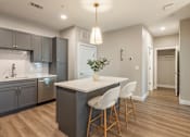 Thumbnail 2 of 66 - A modern kitchen with a white island and grey cabinets.at Preserve at Sycamore Creek, Missouri 65065