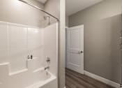 Thumbnail 32 of 66 - A white tiled bathroom with a white bathtub and a white door.at Preserve at Sycamore Creek, Osage Beach, MO 65065