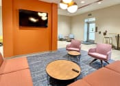 Thumbnail 8 of 17 - clubroom/resident lounge with sofa, two arm chairs, coffee table and television  at The Residences at Delmar DivINe, St Louis, MO