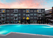 Thumbnail 31 of 36 - A large swimming pool in front of a building with a sunset in the background. at The Cunningham Apartments, West Des Moines, IA, 50266