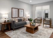 Thumbnail 12 of 71 - Living room with rich plank flooring, oversized windows with custom shades, full size sofa, two arm chairs, coffee table and end table at The Flats & Terraces at Wildhorse Village, Missouri, 63005